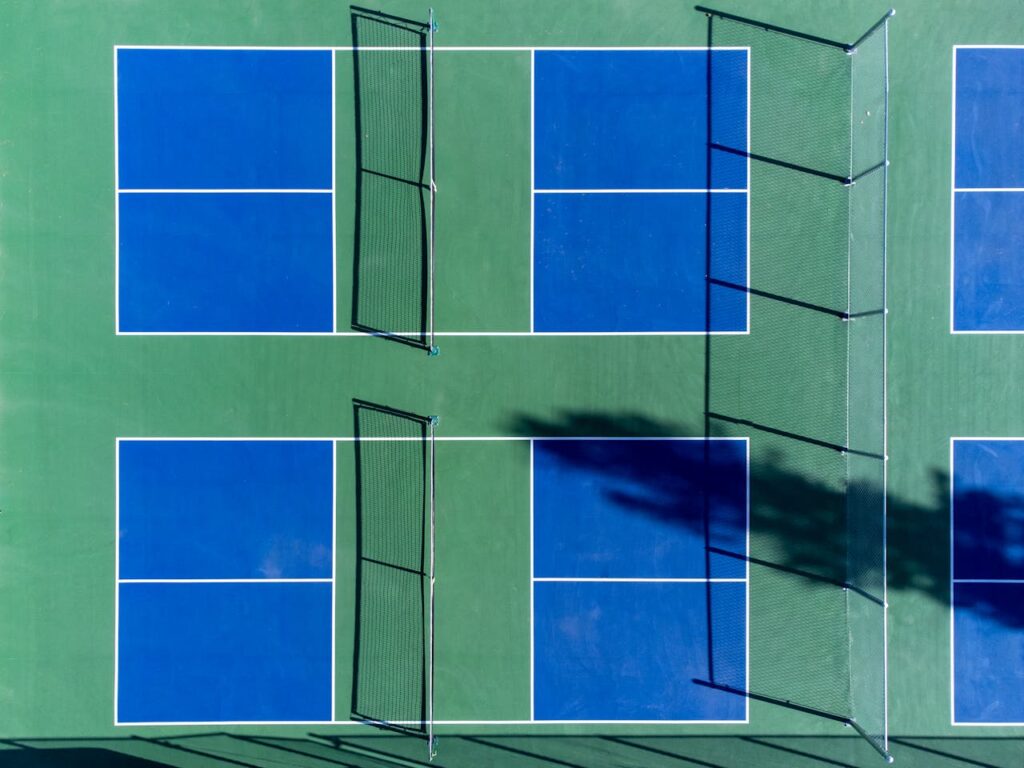 Top-down photo of vibrant blue and green sports courts with nets, perfect for recreational activities.