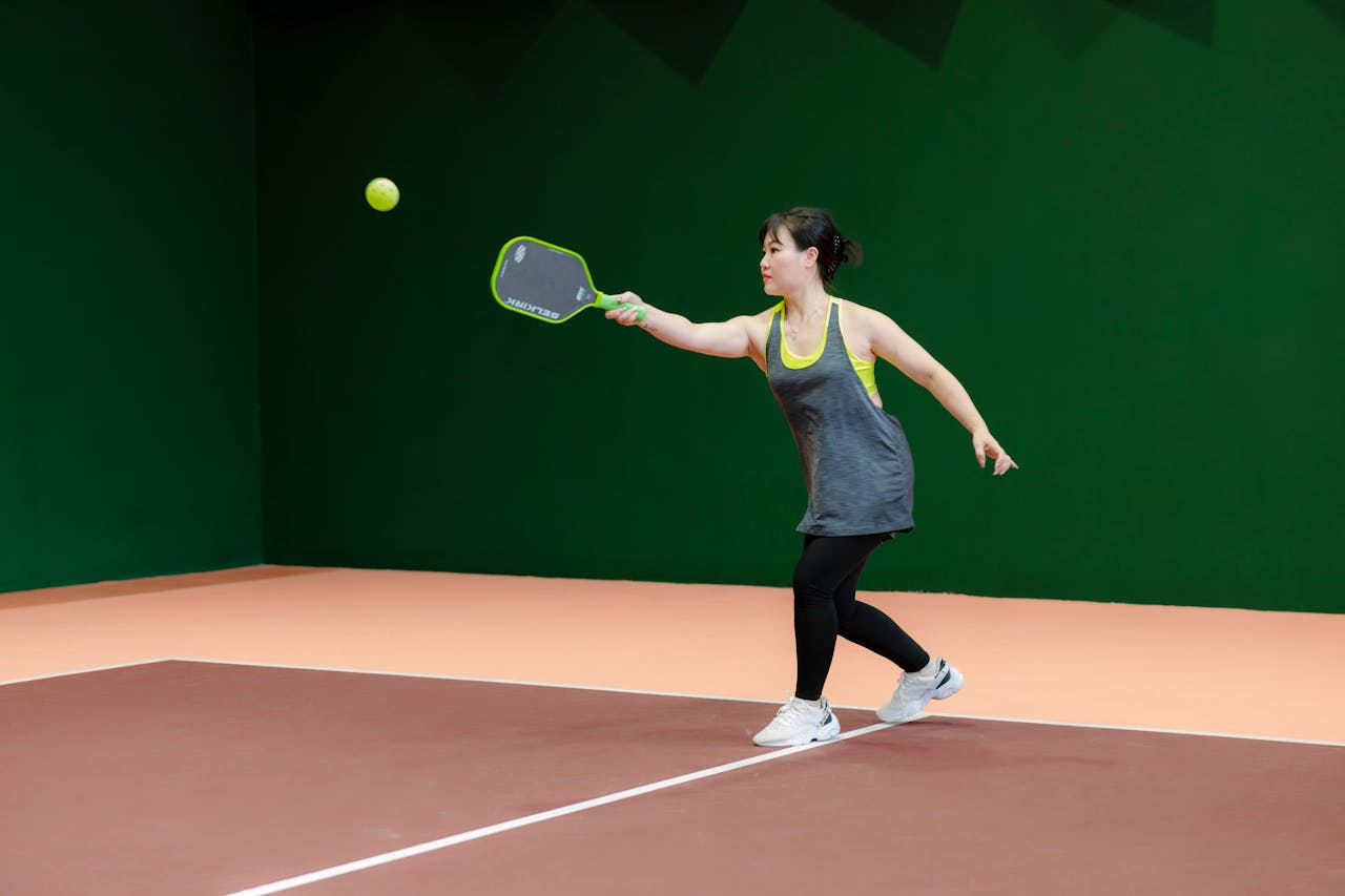 our-journey-02 A woman engaging in pickleball on an indoor court, showcasing athletic skill and focus.