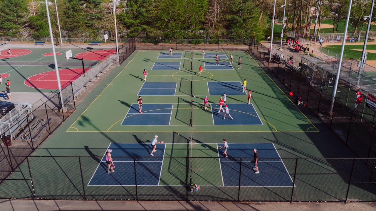 A lively pickleball game at outdoor courts in Philadelphia, captured from above on a sunny day.